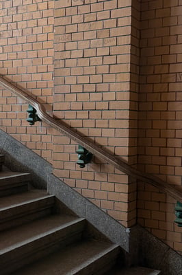 a brick wall with a staircase, wooden railings with green decorative metal fixtures.