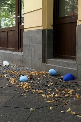 balloons on the ground next to a building with fallen leaves