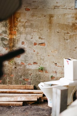 a broken toilet by a brick wall