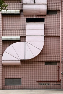 a wide giant curved pink vent on the side of a building building finely tiled with pink square tiles