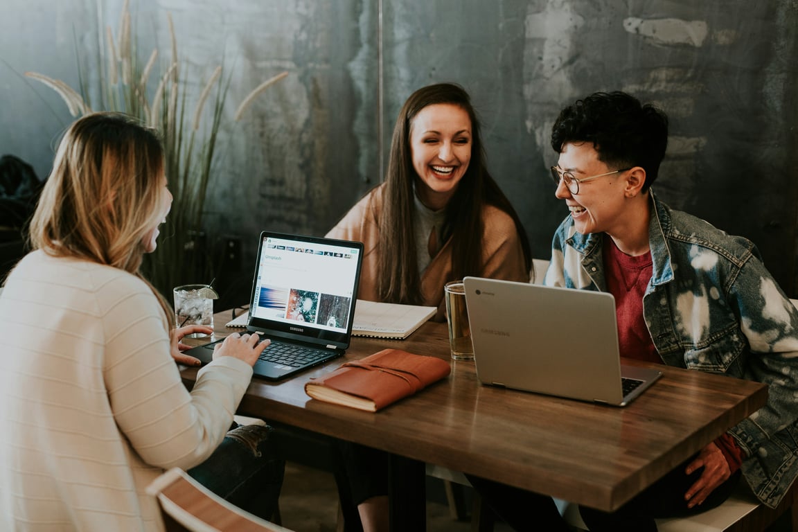 three people sitting in front of table laughing togeter