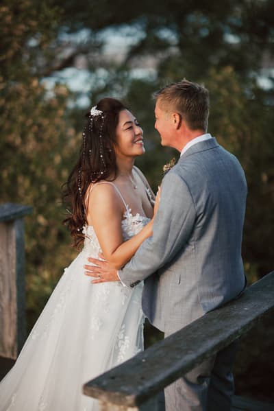 Bride Jheng and groom Dane embrace and smile at each other outdoors. Engagement reception by She Said Yes.