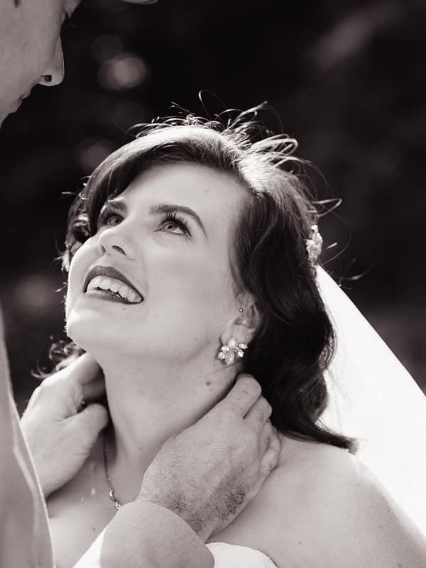 The bride Holly looks up at the groom Paul as he gently holds her neck outdoors at Kwila Lodge.
