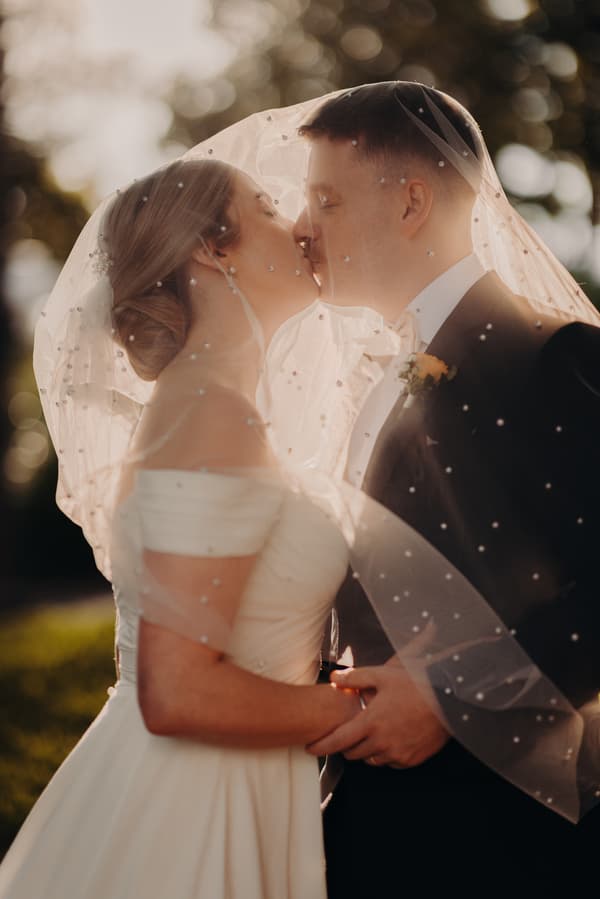 Courtney and Liam share a kiss under Courtney's veil during a couple portrait session at Tiffany's Maleny.