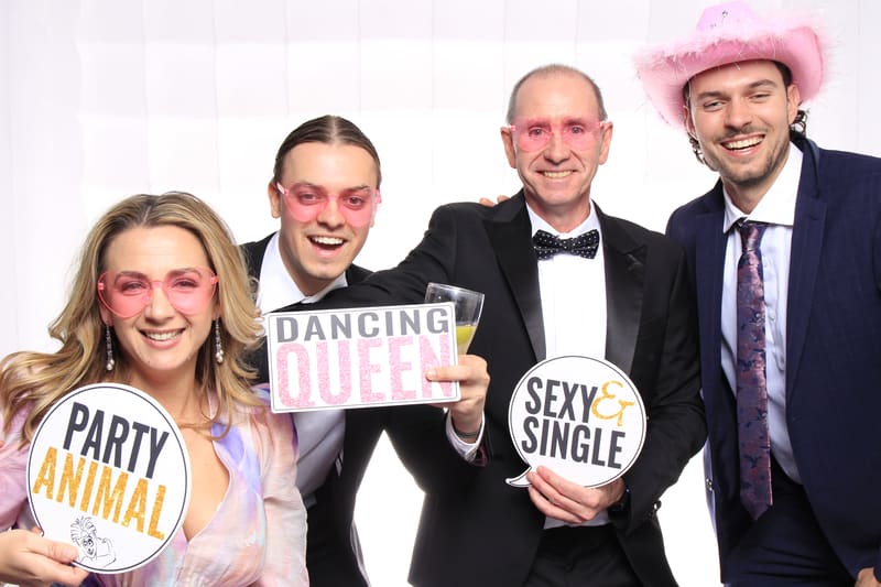 Group of four guests in pink sunglasses holding fun signs.