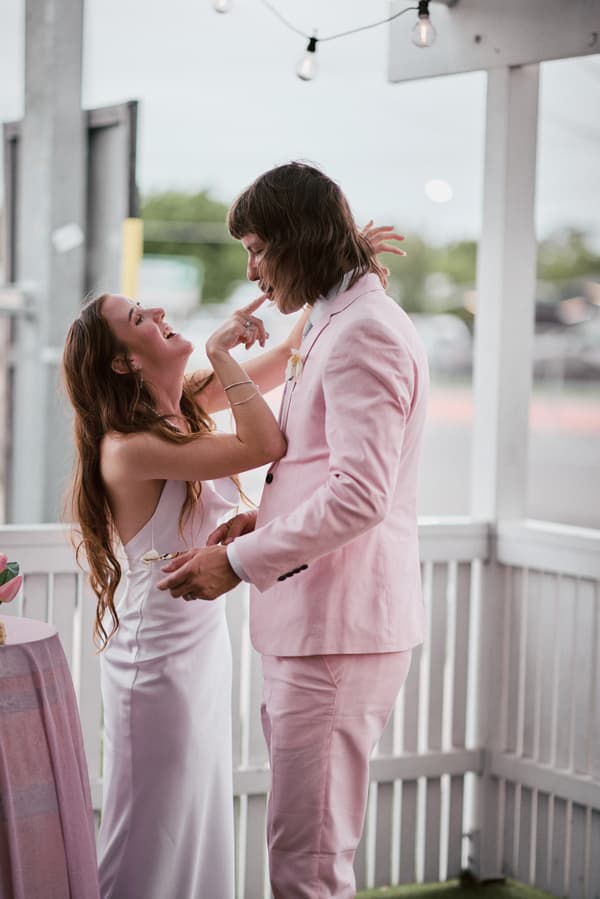 Olivia the bride and Jake the groom share a joyful moment on the reception stage at White Horse Ranch, with Olivia playfully touching Jake's face as he holds a piece of cake.