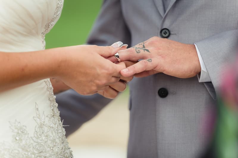 The bride Kelly places a wedding ring on the groom Shane's finger during their ceremony at Novotel Sunshine Coast Resort.