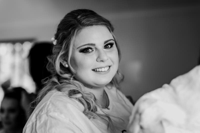 The bride Annie is smiling indoors, likely during preparation, with blurred figures in the background.