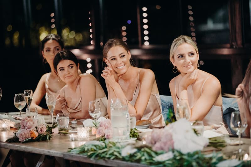 Bridesmaids seated at a table with floral arrangements and glassware during the reception at Preston Peak Winery Functions Centre.