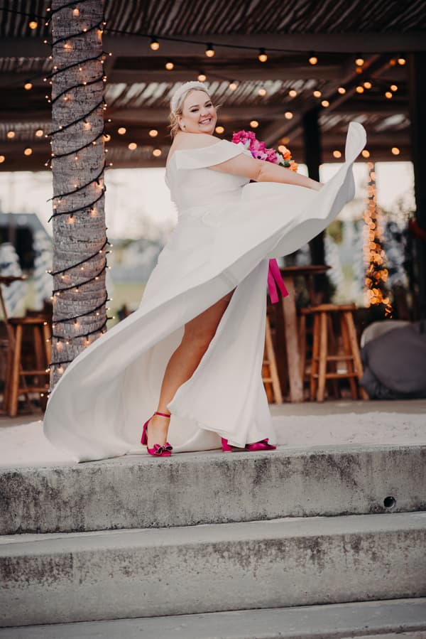 The bride Jacquelyne twirls in her white wedding dress holding a bouquet with pink flowers at Sandstone Point Hotel.