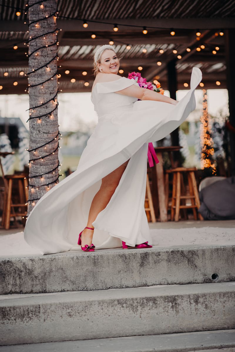 The bride Jacquelyne twirls in her white wedding dress holding a bouquet with pink flowers. Spring engagement session Brisbane by She Said Yes.