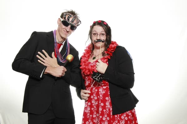 A man and a woman pose playfully with props in a photo booth.