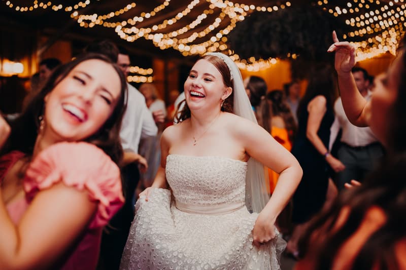 The bride Lilly dances and smiles at Yabbaloumba Retreat — The Shed during the wedding reception, surrounded by guests.