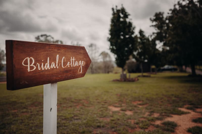 Wooden signpost with 'Bridal Cottage' text in a grassy outdoor area at Preston Peak Winery Functions Centre.