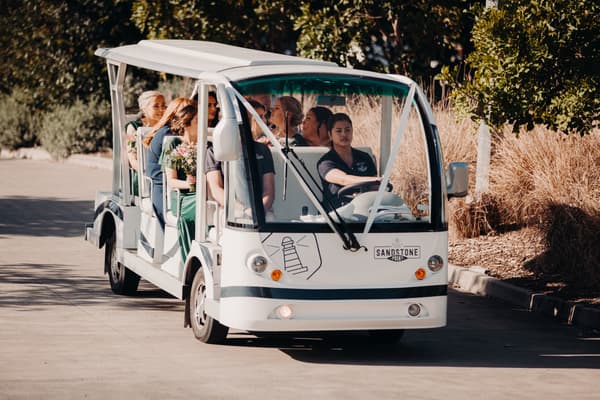Bridesmaids seated in a white open-sided shuttle cart driven by a staff member. Shortest day wedding timeline by She Said Yes.
