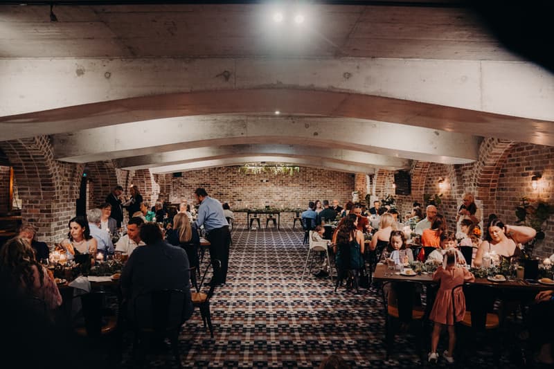 Guests seated at tables dining and socializing during the reception at Sandstone Point Hotel — Cellar.