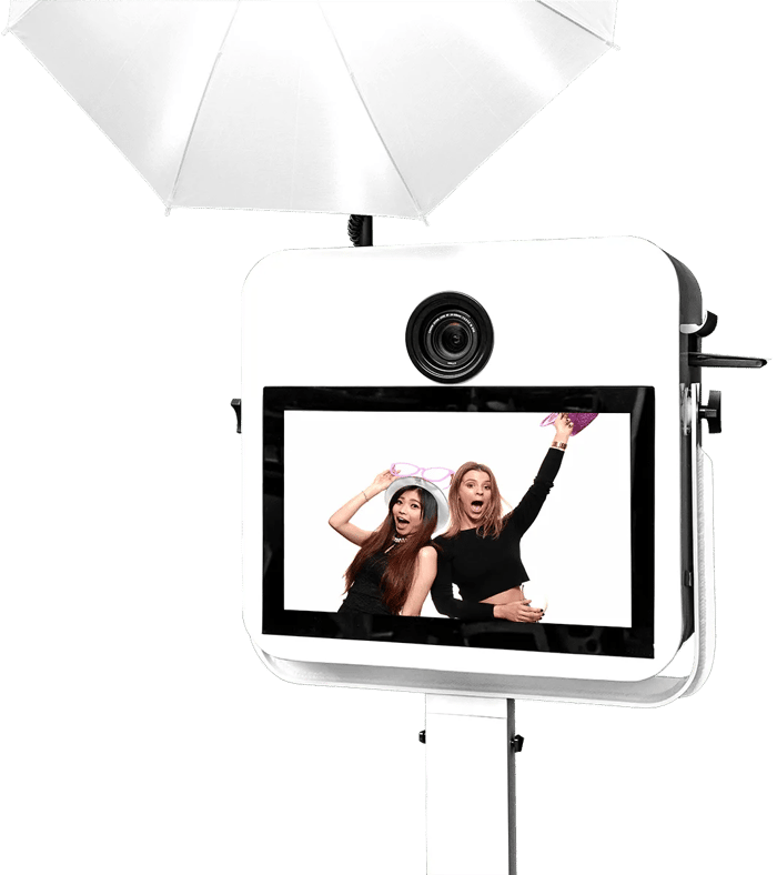 Two women having fun at a She Said YES photo booth with a pink cowboy hat