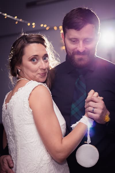 Bride Francesca and groom Ben dance together at the reception in The Malouf Room, with Francesca wearing a white lace dress and pearl necklace and Ben in a dark shirt and plaid tie. Wedding photographers Brisbane by She Said Yes.