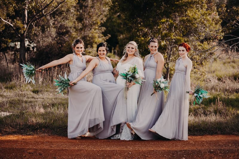 The bride Annie poses with four bridesmaids outdoors at Ocean View Estates, all holding bouquets and wearing long lavender dresses.