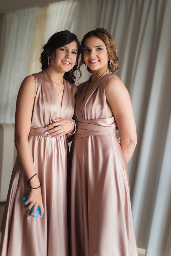 Two bridesmaids in matching blush pink satin dresses pose together indoors at Novotel Sunshine Coast Resort.