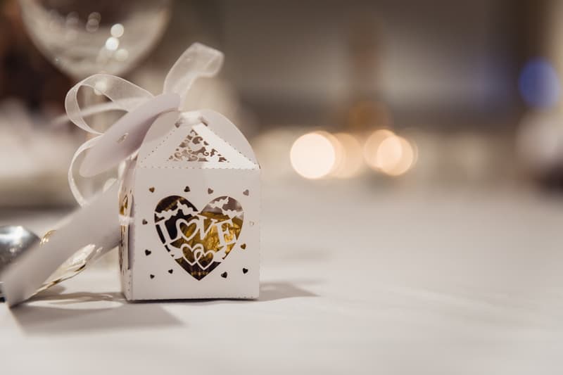 A small white wedding favor box with a heart-shaped cutout and the word 'LOVE' on a table at Novotel Sunshine Coast Resort reception.