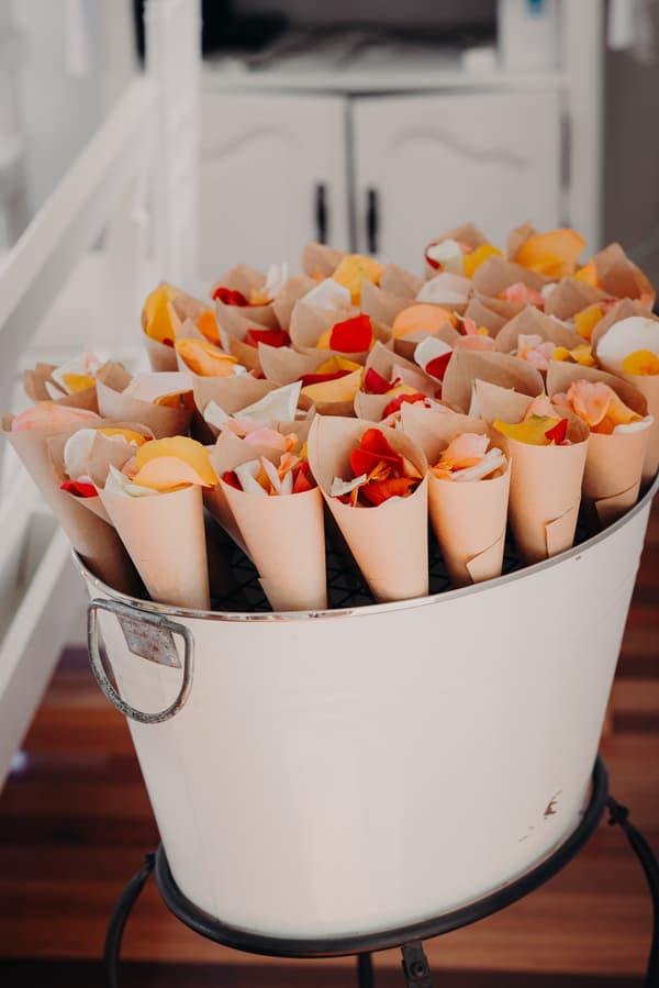 Paper cones filled with assorted rose petals arranged in a white metal bucket at Tiffany's Maleny — Chapel.