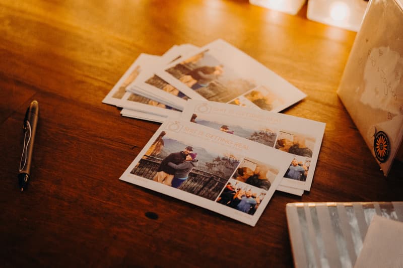 Stack of wedding photo booth prints with images of the couple on a wooden table at Sandstone Point Hotel — The Cellar reception stage.