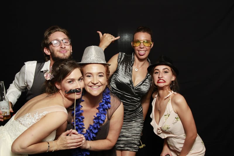 Group of guests posing with props in a photo booth.