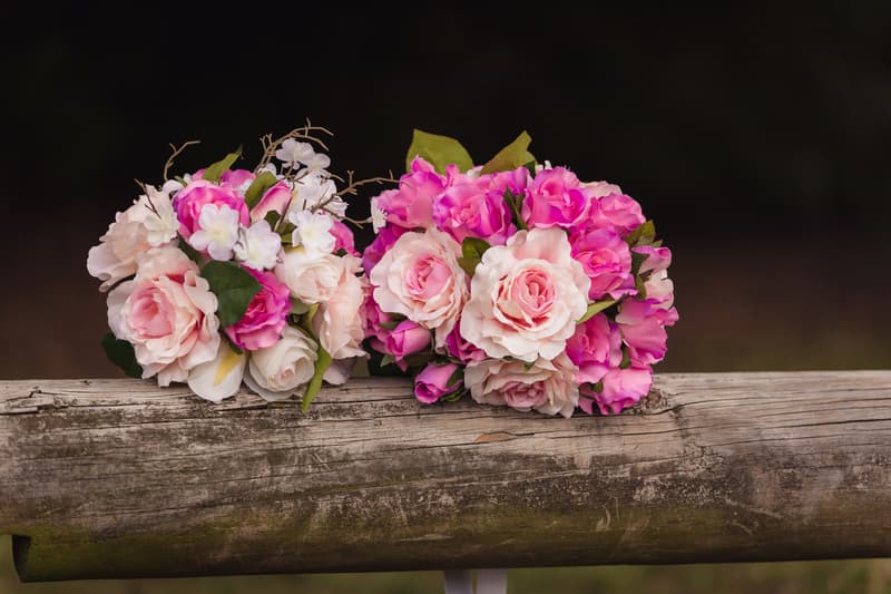 Two bouquets of pink and white flowers resting on a weathered wooden log at Novotel Sunshine Coast Resort.