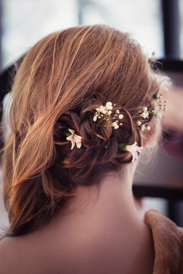 Close-up rear view of the bride's styled hair adorned with small white flowers at Toowong Rowing Club.