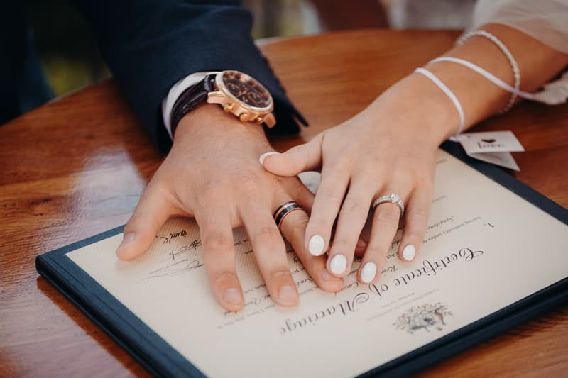 The bride and groom place their hands together on a signed marriage certificate at Sandstone Point Hotel — Pavilion.