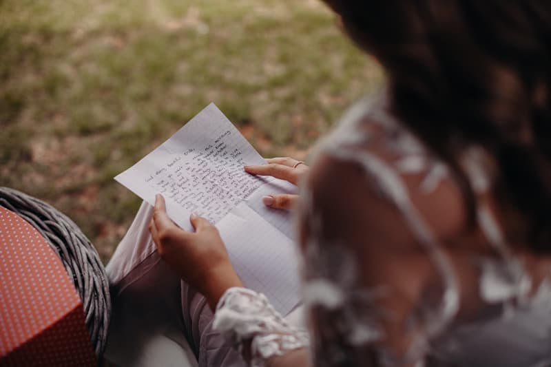 The bride Chelsea is seated outdoors at Preston Peak Winery Functions Centre, reading a handwritten letter.