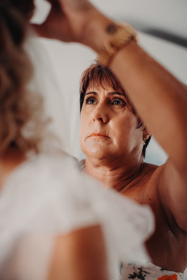 The mother of the bride adjusts Krystal's hair or veil during bridal preparation.
