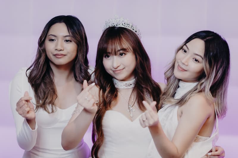 The bride wearing a tiara and white dress poses with two bridesmaids in white dresses at the reception stage of Royal on the Park.