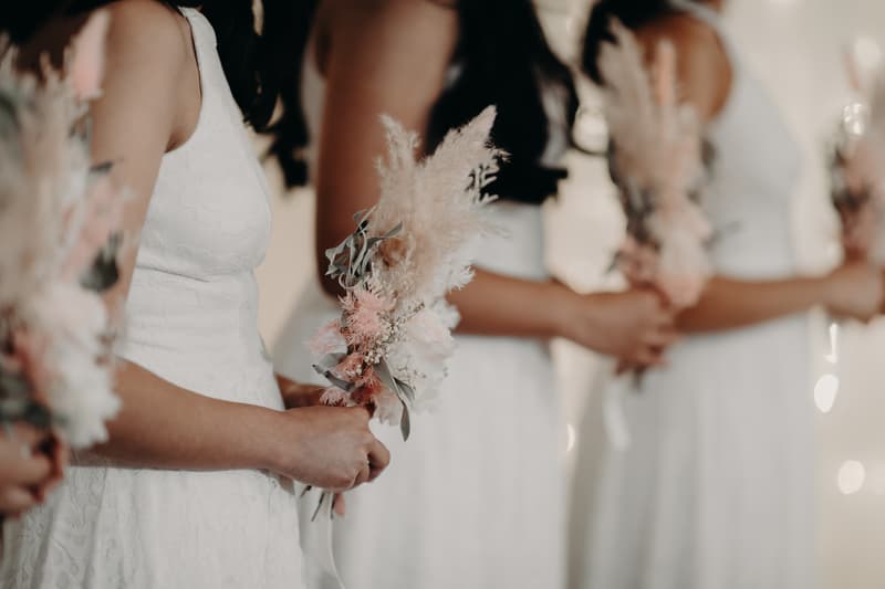 Bridesmaids stand in a row holding bouquets of dried flowers at Royal on the Park.