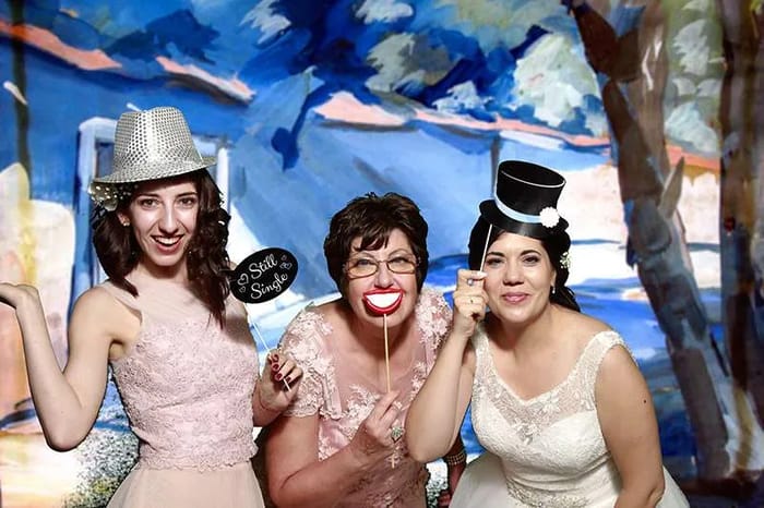 Three women having fun with props and the green screen photo booth