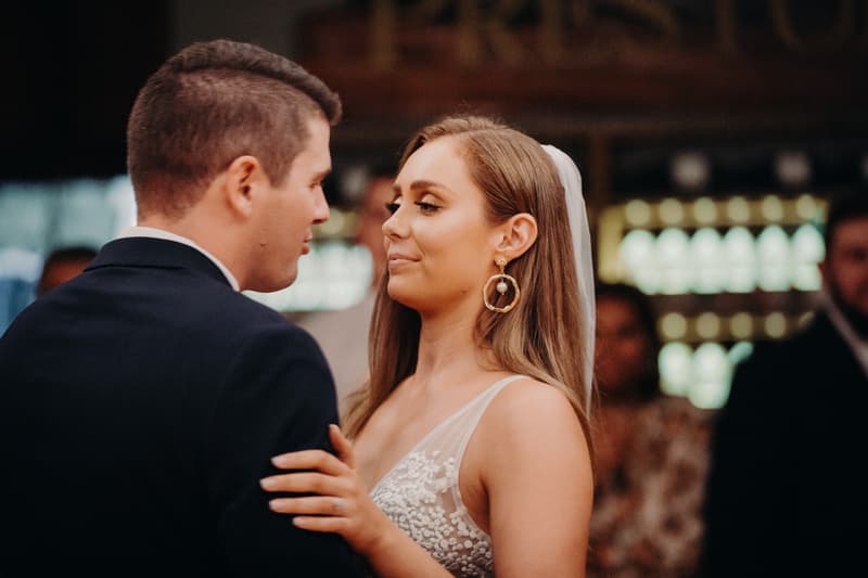 Bride Chelsea and groom Brent share a close moment on the reception stage at Preston Peak Winery Functions Centre, with Chelsea wearing a white wedding dress and Brent in a dark suit.