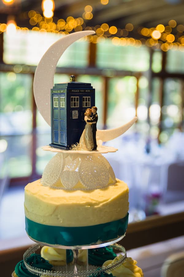 Wedding cake at Kwila Lodge topped with a bride and groom figurine, a blue police box, and a crescent moon decoration.
