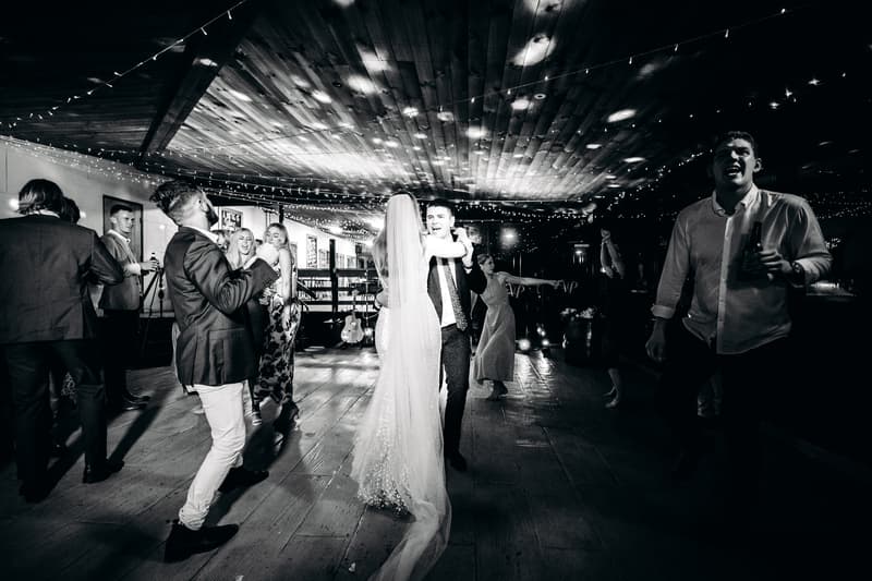 Chelsea and Brent dance together on the dance floor at Preston Peak Winery Functions Centre reception, surrounded by guests dancing and socializing under string lights.