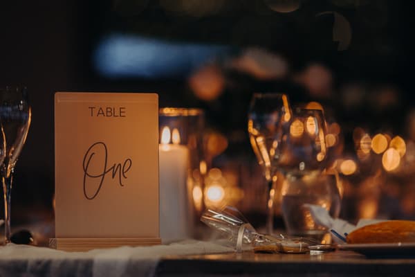 Table One at Preston Peak Winery Functions Centre set with wine glasses, a lit candle, wrapped cookies, and a bread roll on a plate.