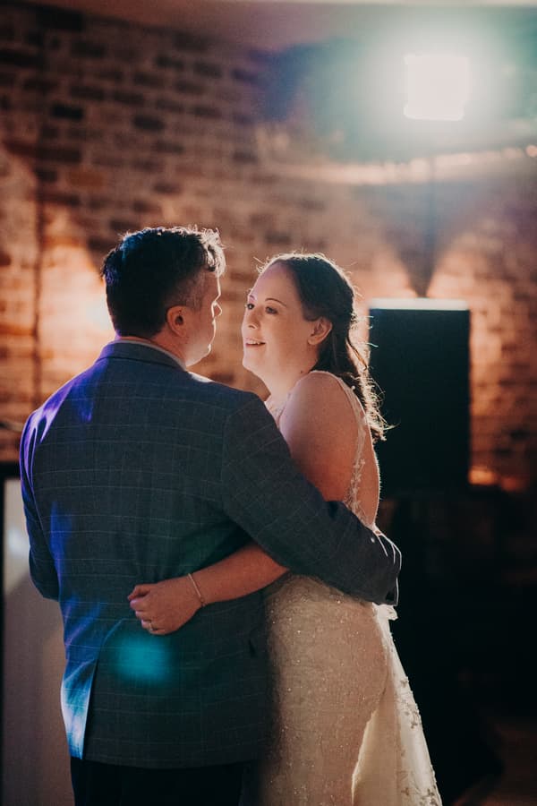 Rebecca and Dale share a dance at the Sandstone Point Hotel — Cellar with exposed brick walls and soft lighting in the background.