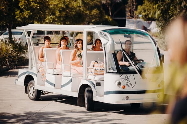 Bridesmaids seated in a white open-sided shuttle vehicle, with a driver in front. Wedding family photos by She Said Yes.