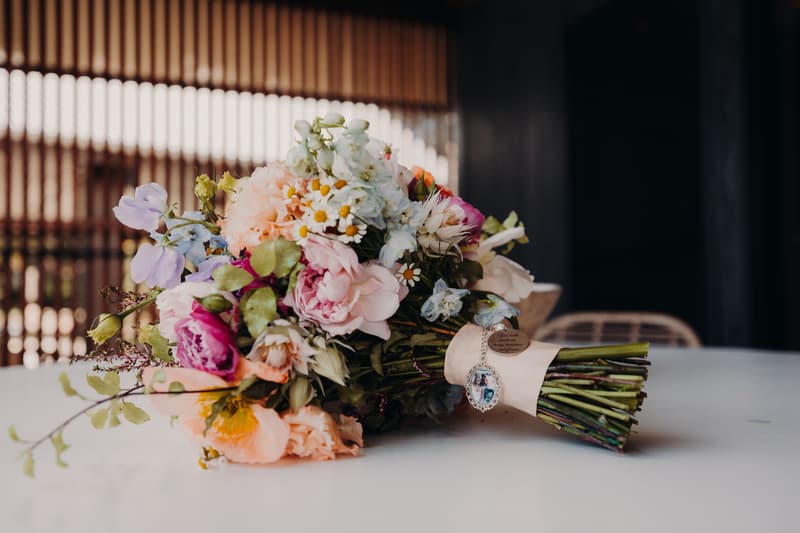 A bridal bouquet with mixed flowers including pink, white, and purple blooms lies on a white table at Sandstone Point Hotel.