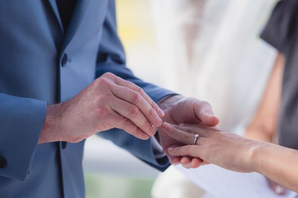 Jason places a wedding ring on Wing's finger during the ceremony at Bilinga Beach Weddings — The Terrace.
