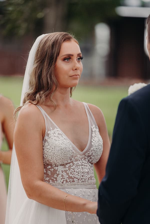 The bride Chelsea stands facing the groom Brent during their wedding ceremony at Preston Peak Winery Functions Centre.