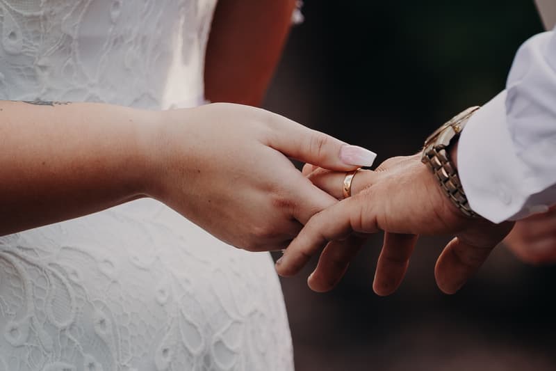 The bride Annie places a wedding ring on the groom Trent's finger during the ceremony at Ocean View Estates.
