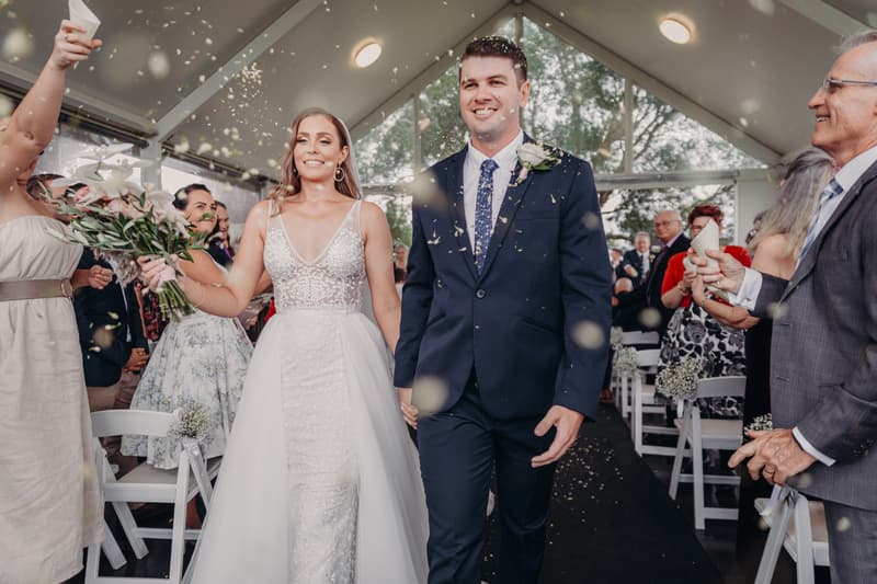 Bride Chelsea and groom Brent walk down the aisle at Preston Peak Winery Functions Centre as guests throw confetti.
