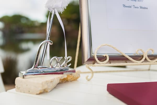 A decorative silver 'Love' sign on a stone base next to a framed document on a white table at Novotel Sunshine Coast Resort.