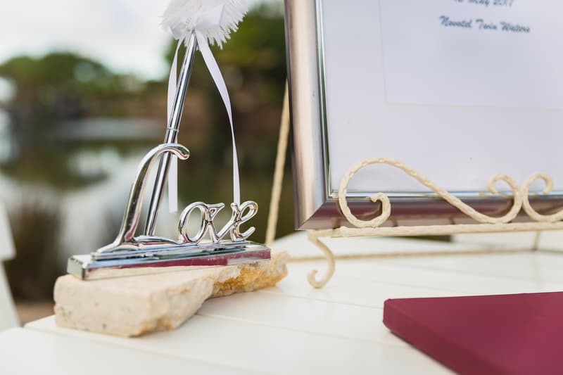 A decorative silver 'Love' sign on a stone base next to a framed document on a white table at Novotel Sunshine Coast Resort.
