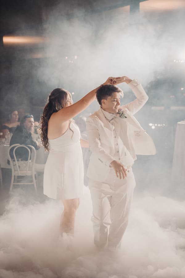 Brides Brooke and Tiffany dance together on a fog-covered floor at the Sandstone Point Hotel — The Pumicestone Room reception.